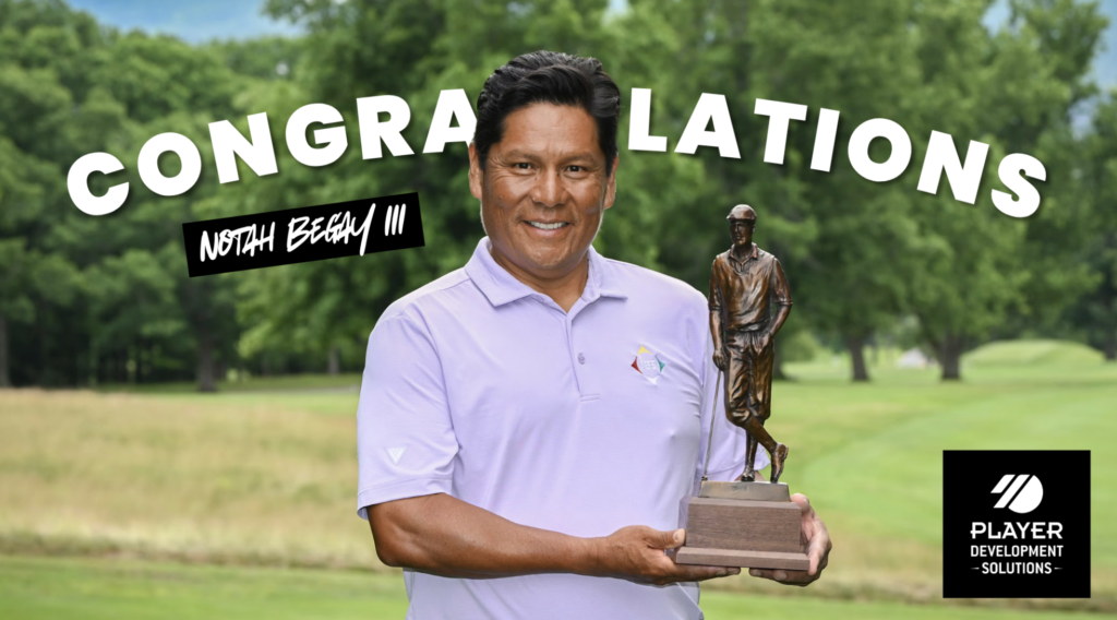 Man in lavender polo holding a trophy outdoors with a 'CONGRATULATIONS' banner across the scene, golf course background.